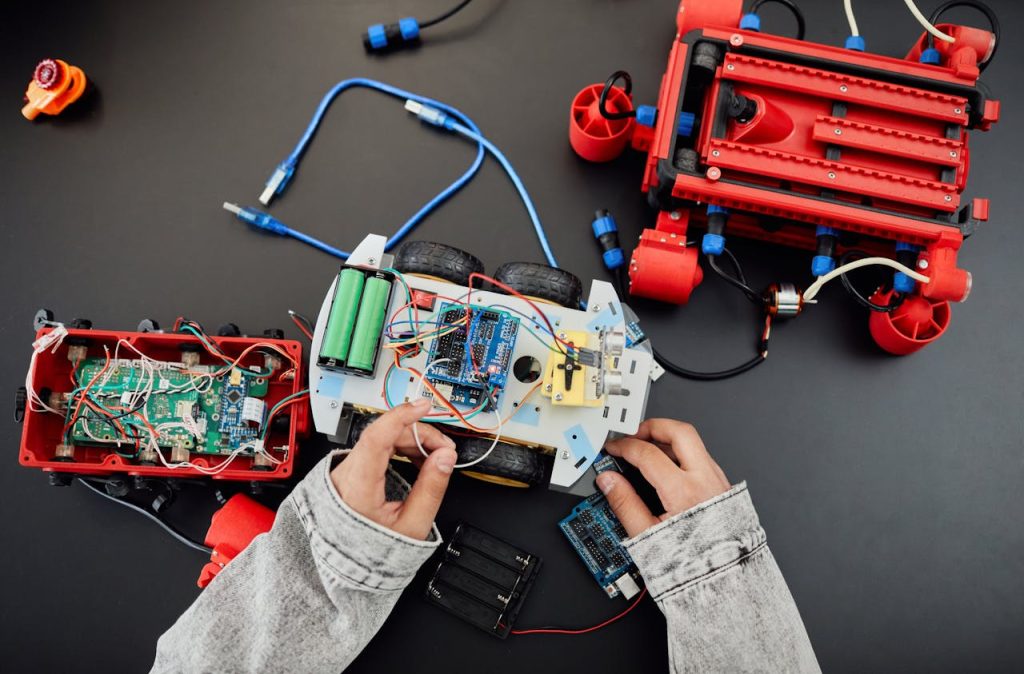 Young hands working on a robotics project with toy cars and circuits, focusing on innovation and education.